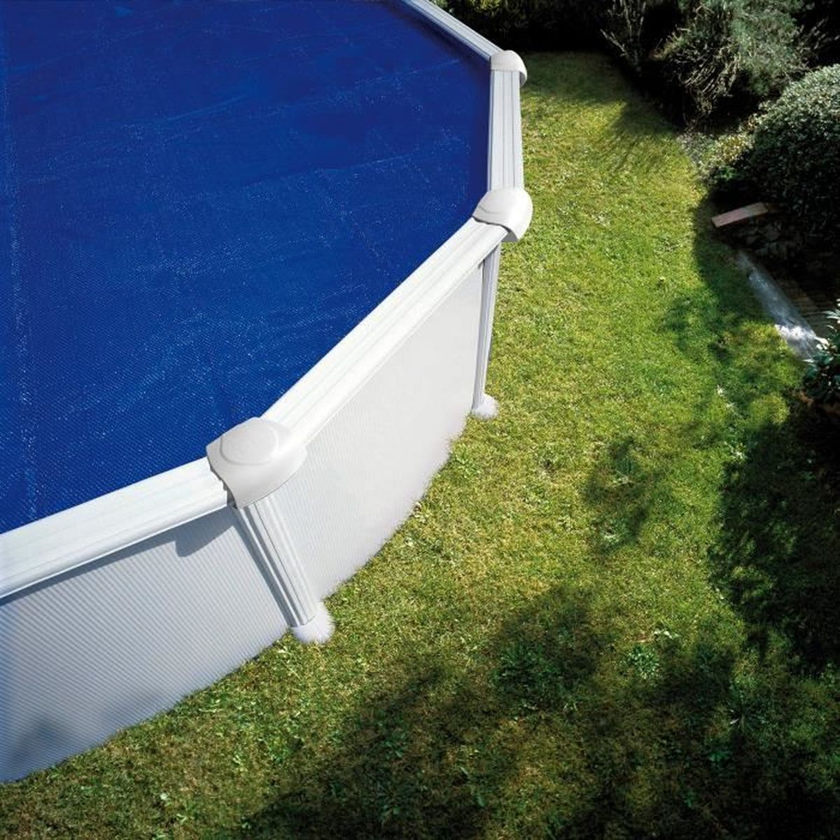 Ein aufblasbarer Pool mit blauer Abdeckung steht auf einem Rasen.