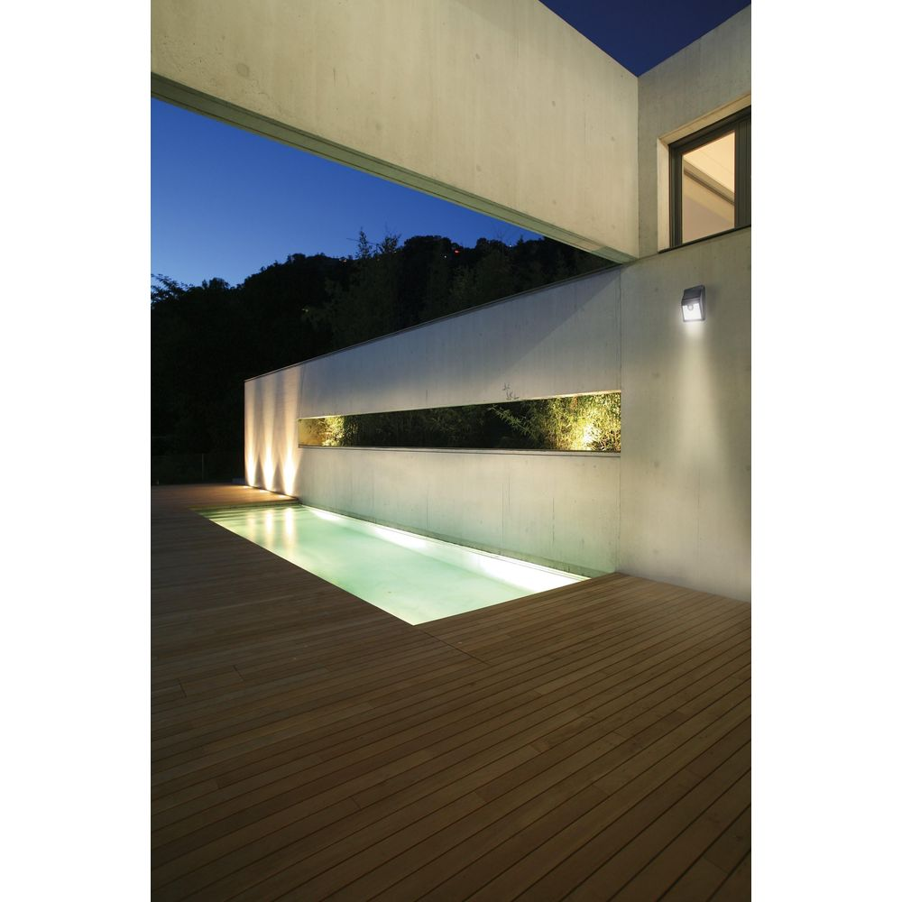 Ein moderner Außenbereich mit Pool und Holzdeck bei Nacht, beleuchtet.
