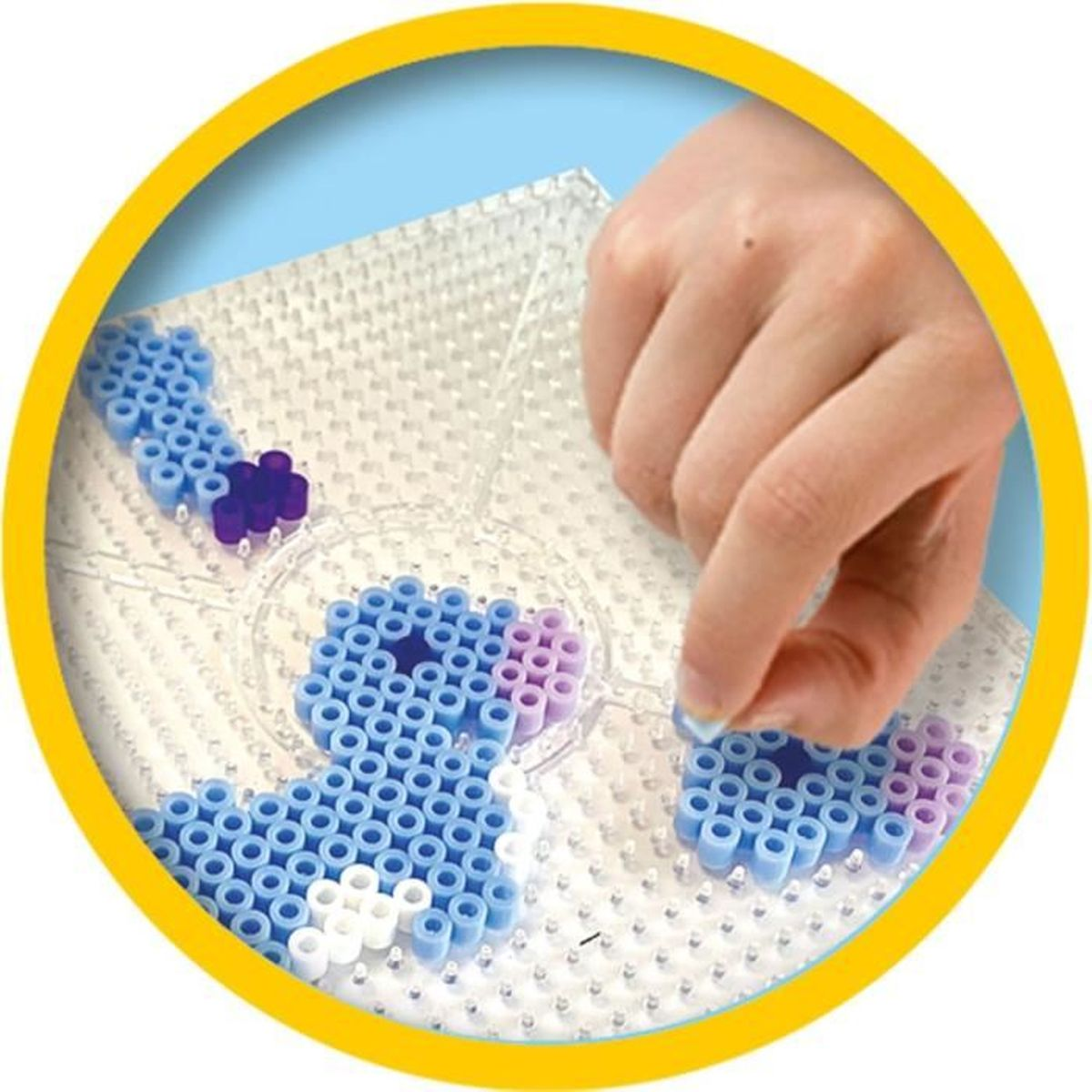Eine Hand platziert blaue und lila Perlen auf einer Stiftplatte, um ein Muster zu erstellen.