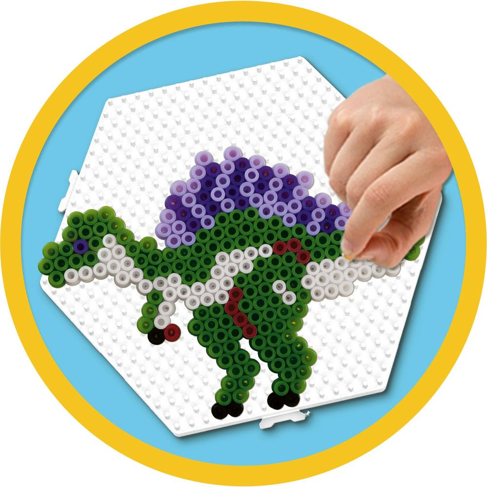 Hand platziert grüne Perlen auf einer Dinosaurierform auf einer weißen Perlenplatte.