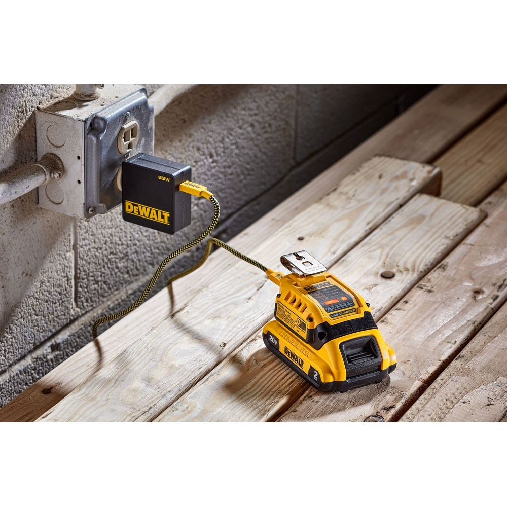 Ein gelber DeWalt USB-Ladegerät mit Kabel ist an eine Wandsteckdose angeschlossen.