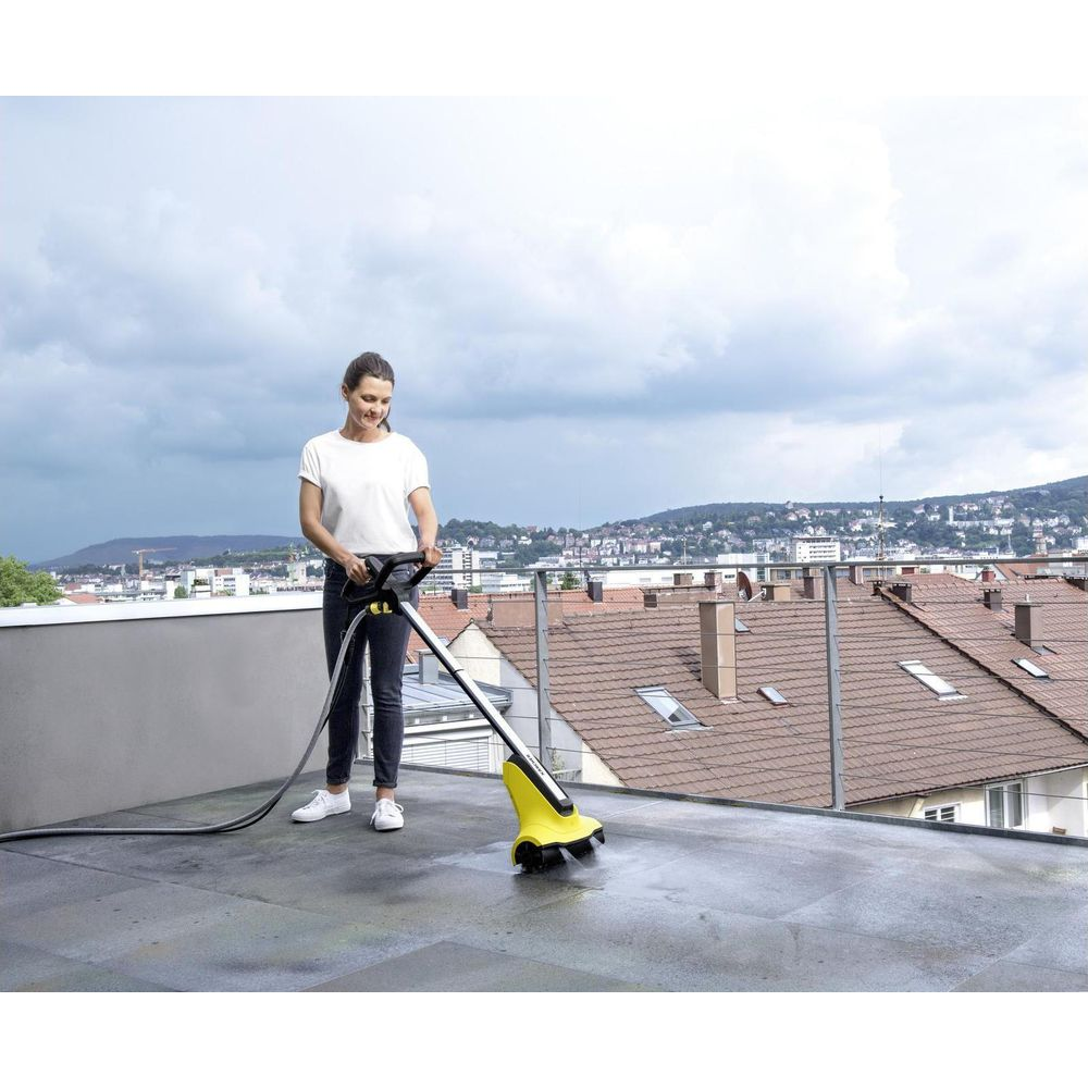 Una donna pulisce una terrazza con un dispositivo di pulizia giallo.