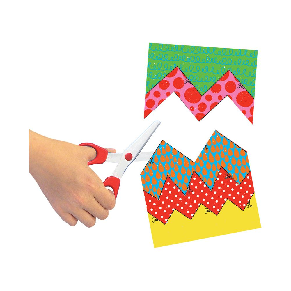 Una mano usa forbici per tagliare carta colorata a motivi a zig-zag.