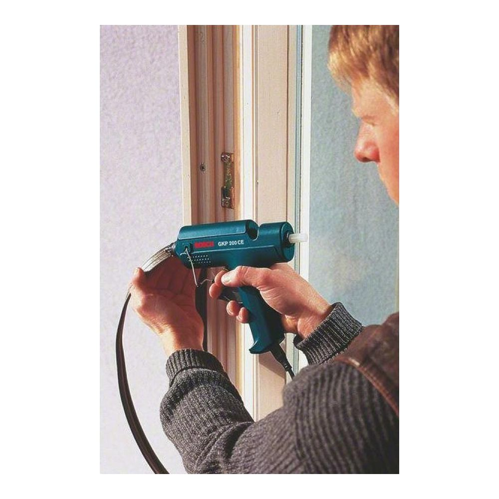 Mężczyzna używa pistoletu do kleju na ramie drzwi.