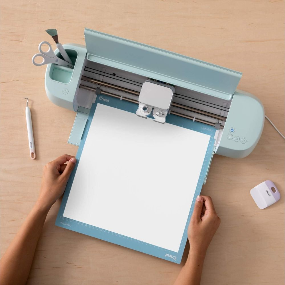 Eine hellblaue Schneidemaschine mit einem Blatt weißem Papier auf der Matte.