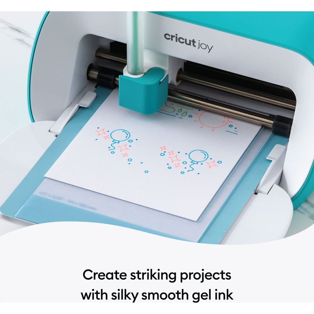 Cricut Joy Maschine zeichnet Ballons und Sonnen mit blauen und orangen Gelschreiber auf weißem Papier.