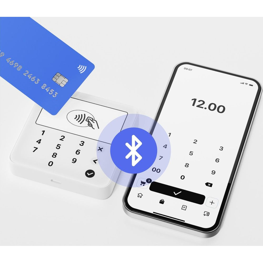 Eine blaue Kreditkarte liegt über einem Kartenleser neben einem Smartphone mit 12.00.