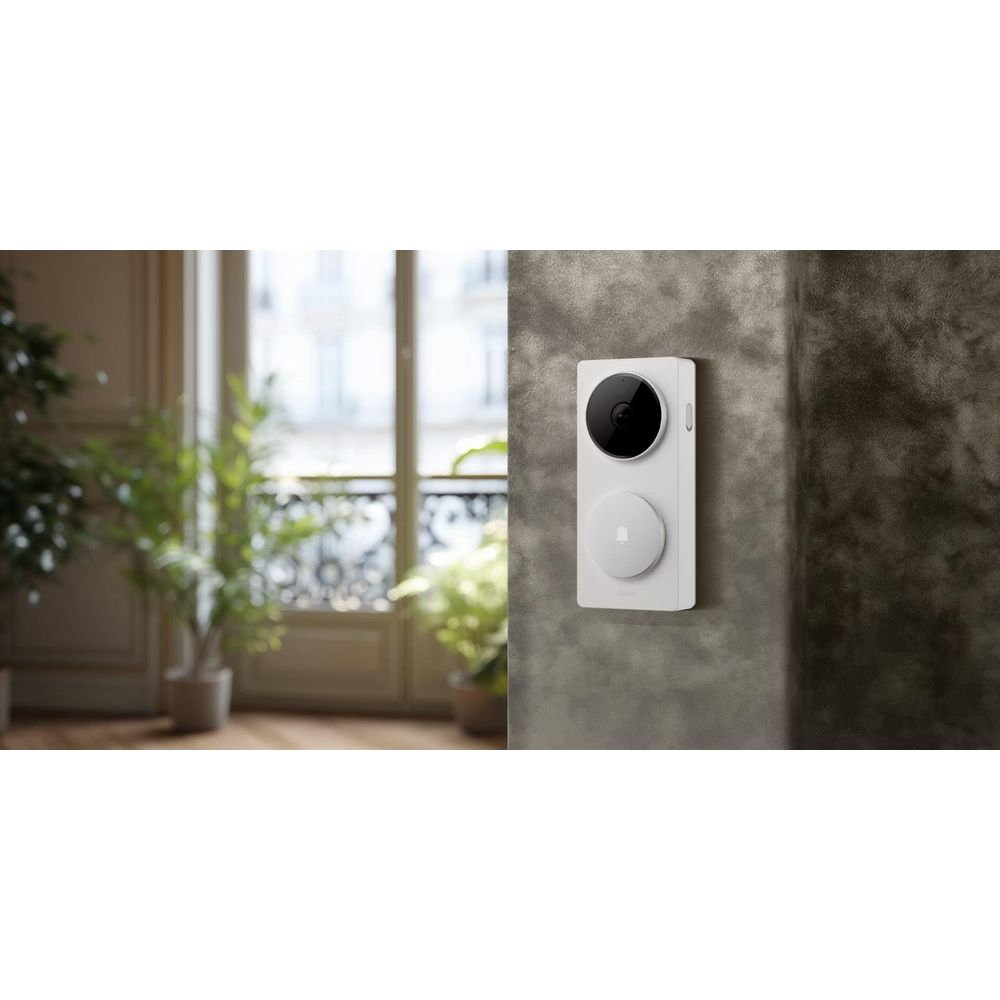 Un campanello bianco con telecamera e pulsante montato su un muro grigio.