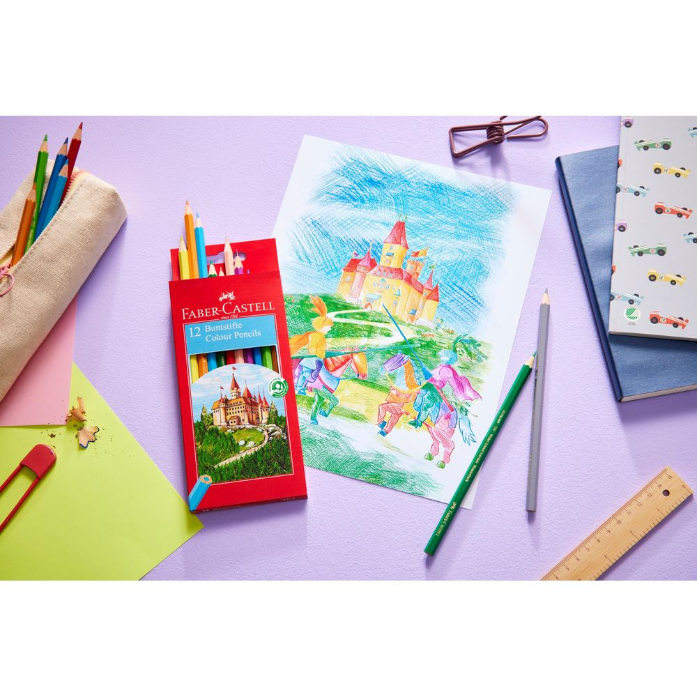 Buntstiftepackung neben einer Zeichnung eines Schlosses und von Pferden. Auch Stifte, Lineal, Brille und Notizbuch.