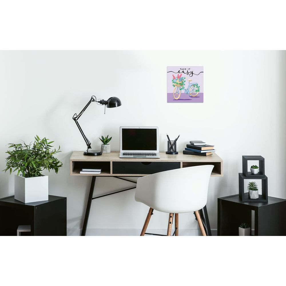 Una scrivania con laptop, lampada e piante. Un quadro di bicicletta è appeso al muro.