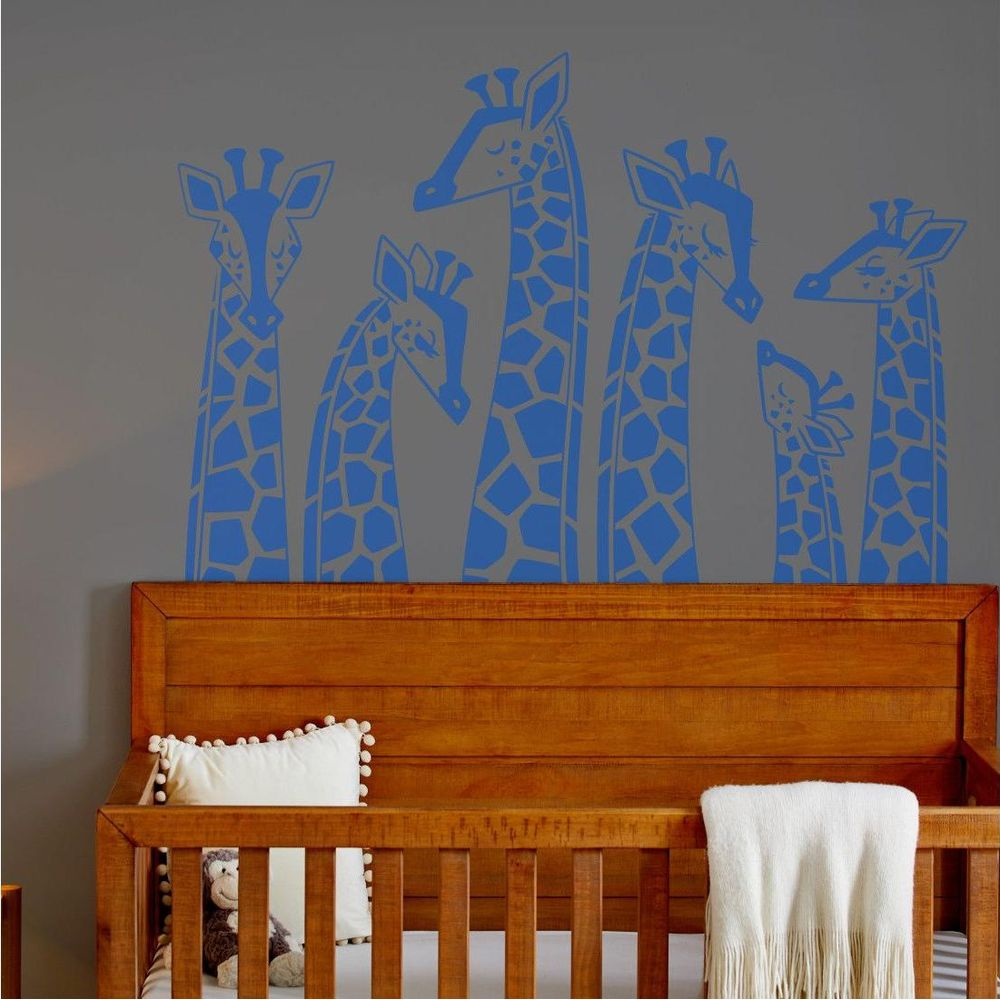 Adesivi blu di giraffe su muro grigio sopra culla.