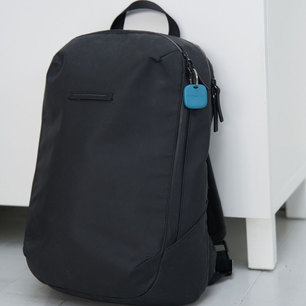 Zaino nero con etichetta blu e zip, appoggiato a un mobile bianco.