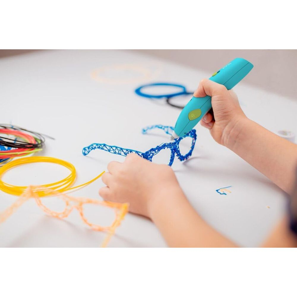 Bambino usa penna 3D per creare occhiali blu, accanto a occhiali arancioni e filamenti.
