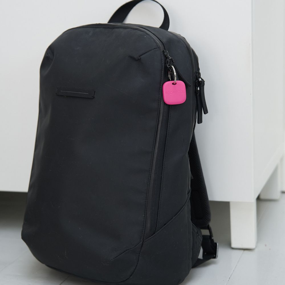 Uno zaino nero con un ciondolo rosa appeso a una cerniera.