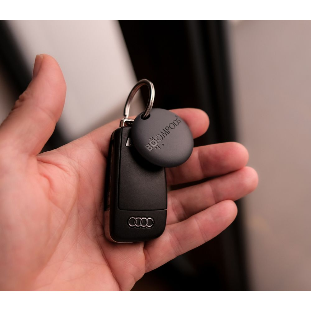 Una mano tiene una chiave per auto Audi con un portachiavi rotondo.