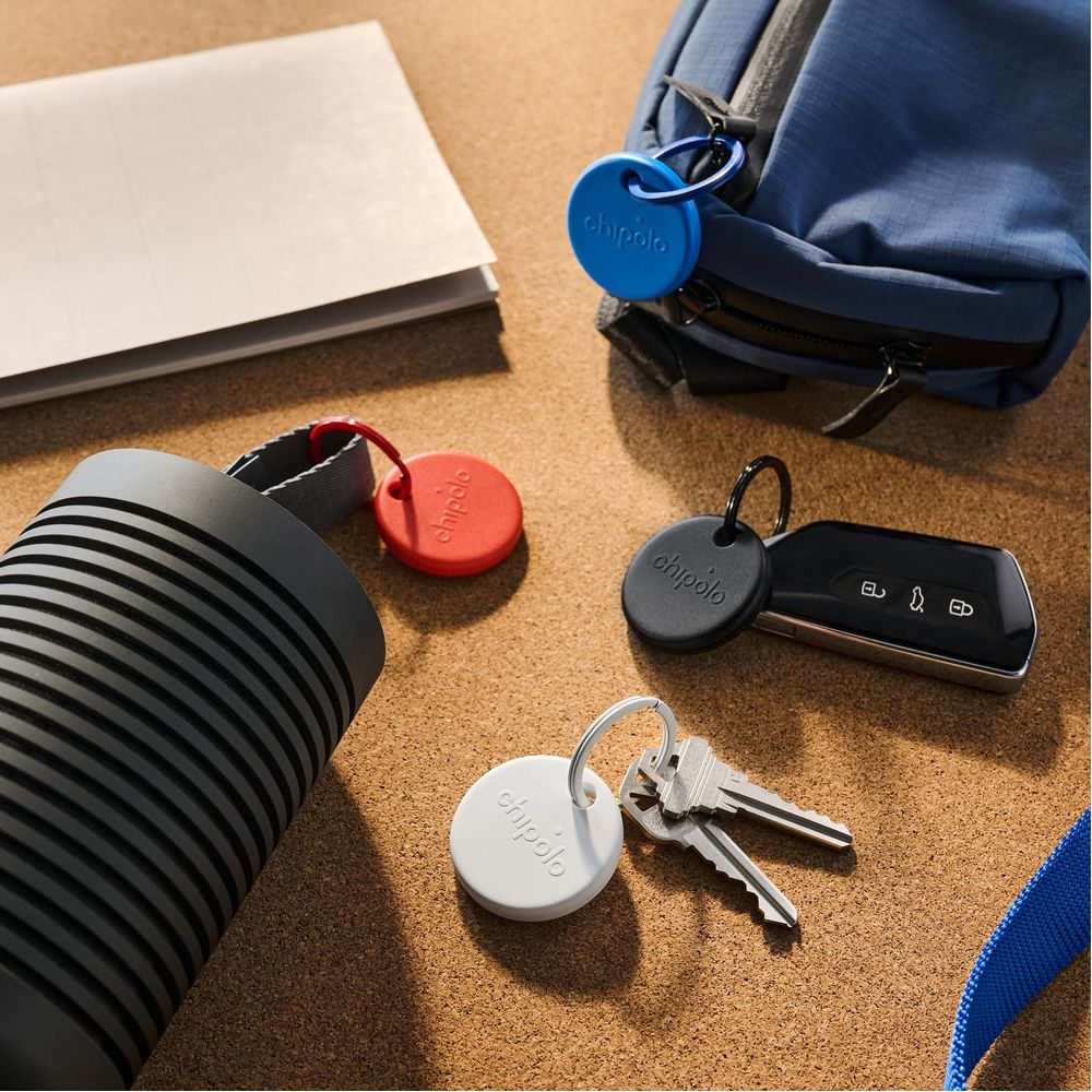Red, white, black, and blue keychains are placed near keys and a bag.