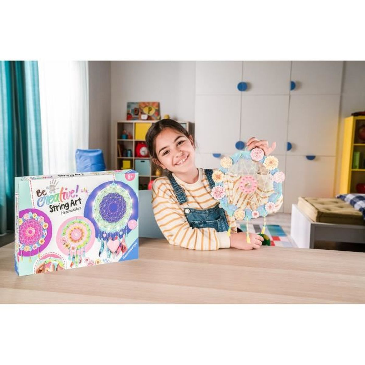 Mädchen hält ein selbstgemachtes Traumfänger-Bastelset mit bunten Blumen und Federn.