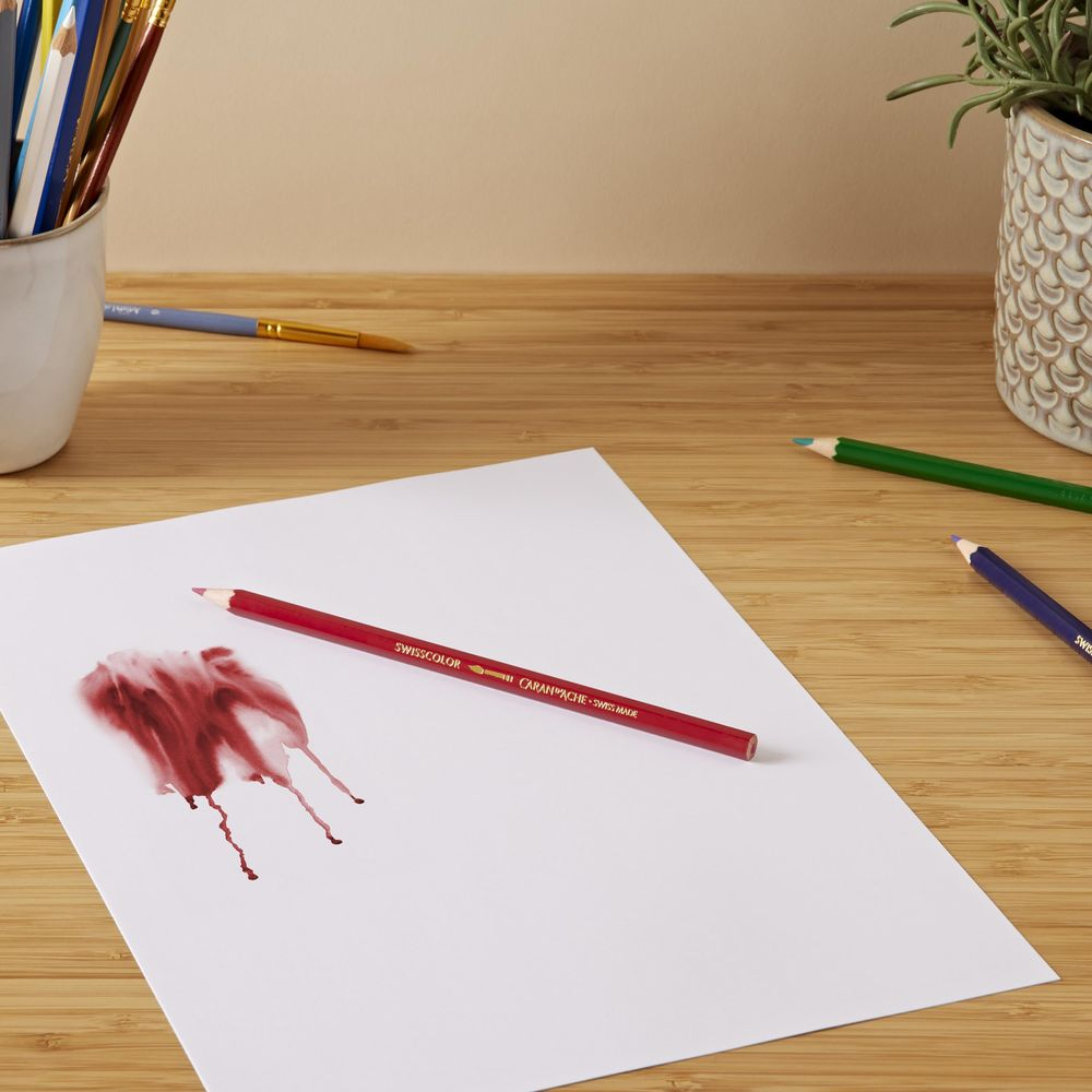 Una matita rossa giace su carta bianca con macchie rosse.