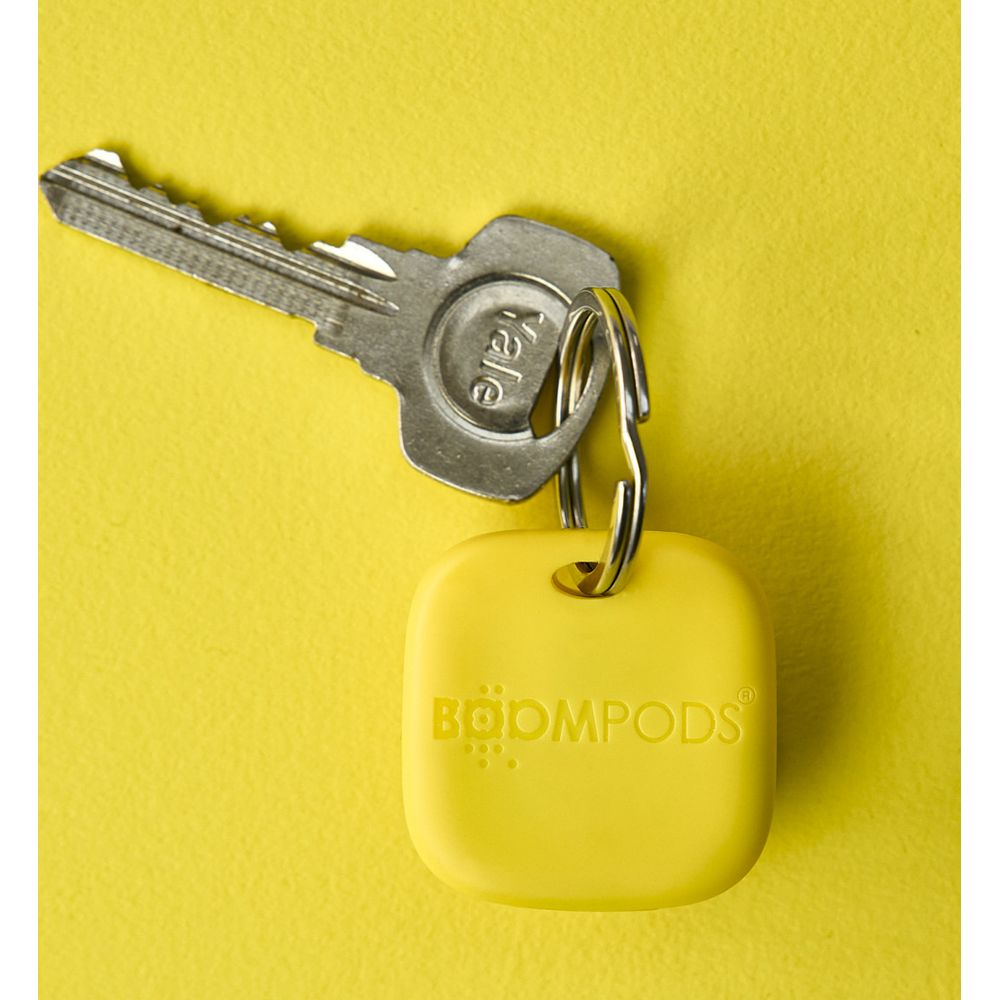 Una chiave Yale con un portachiavi giallo marchiato BOOMPODS su sfondo giallo.