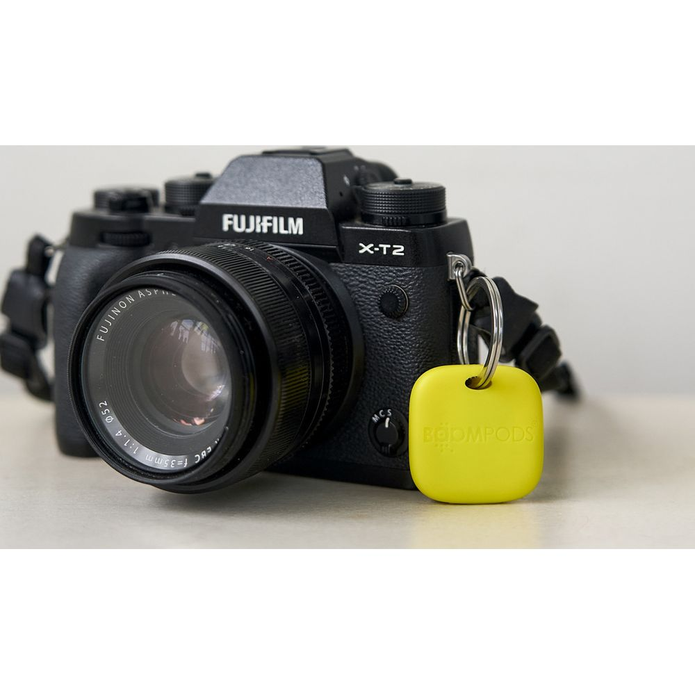 Una fotocamera Fujifilm X-T2 nera con un portachiavi giallo Boompods.