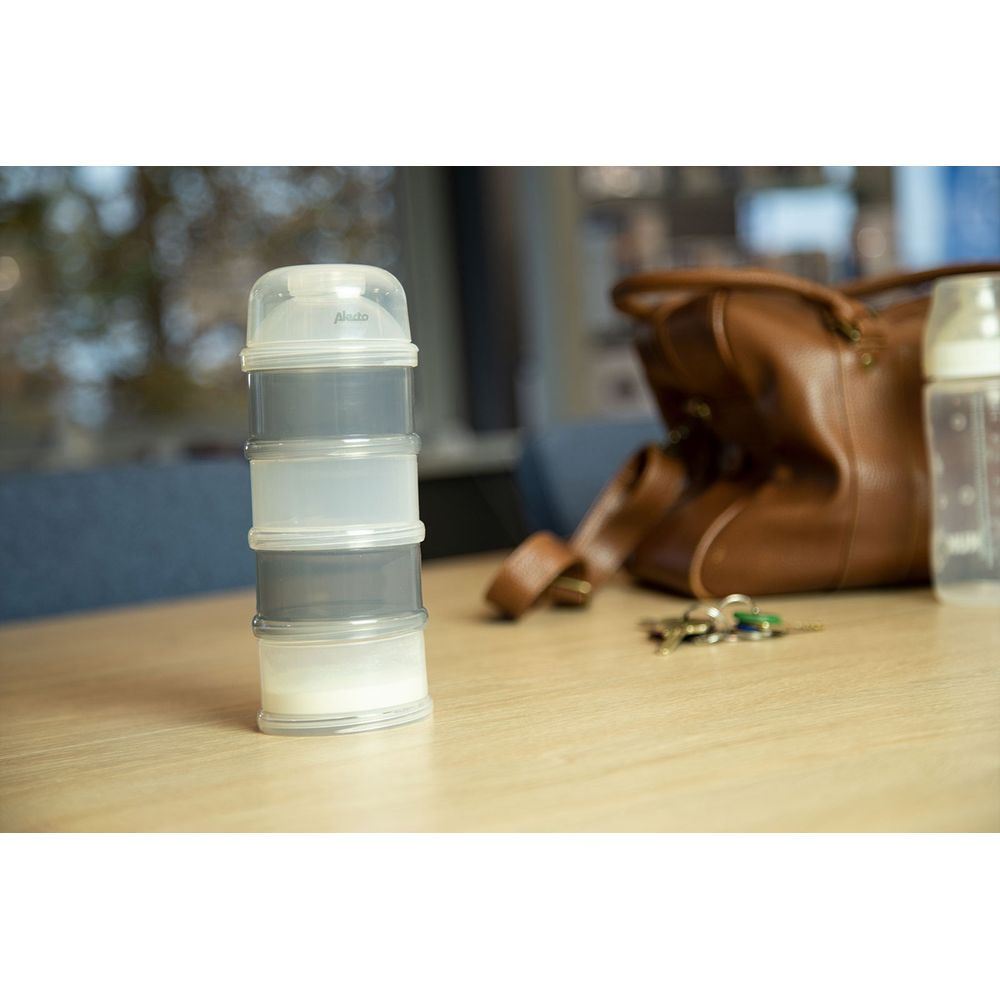 A stacked formula dispenser sits next to a brown leather bag and keys on a wooden table.