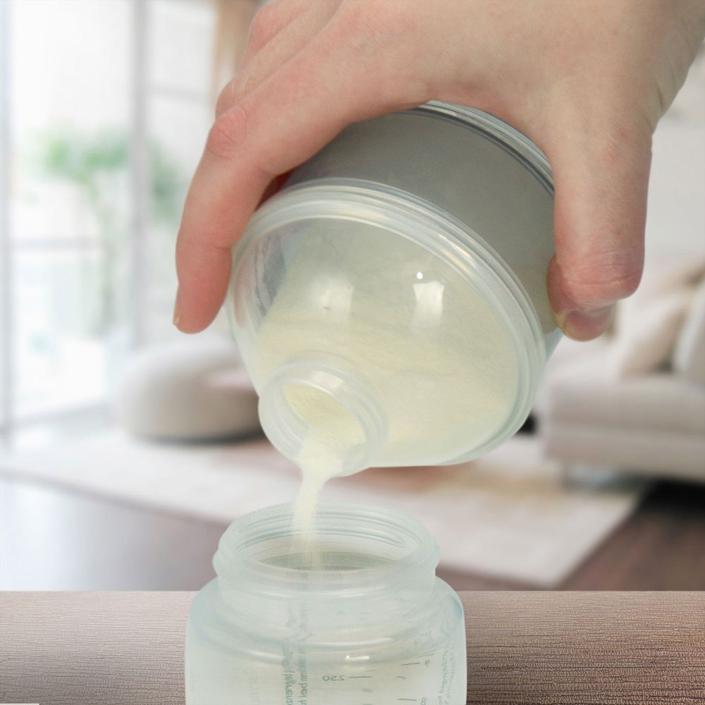 A hand pours powder from a container into a bottle.