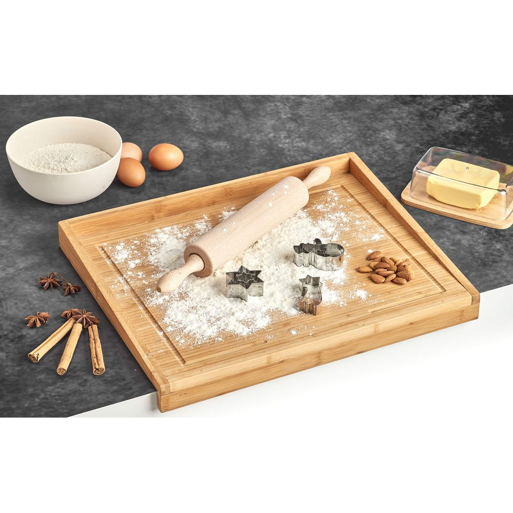 Holzschneidebrett mit Mehl, Backformen, Nüssen, Zimt und Butter.