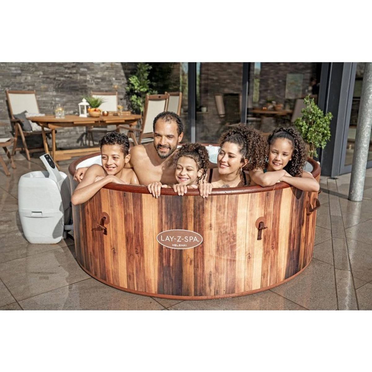 Rodzina kąpie się w drewnianej wannie z hydromasażem na tarasie.