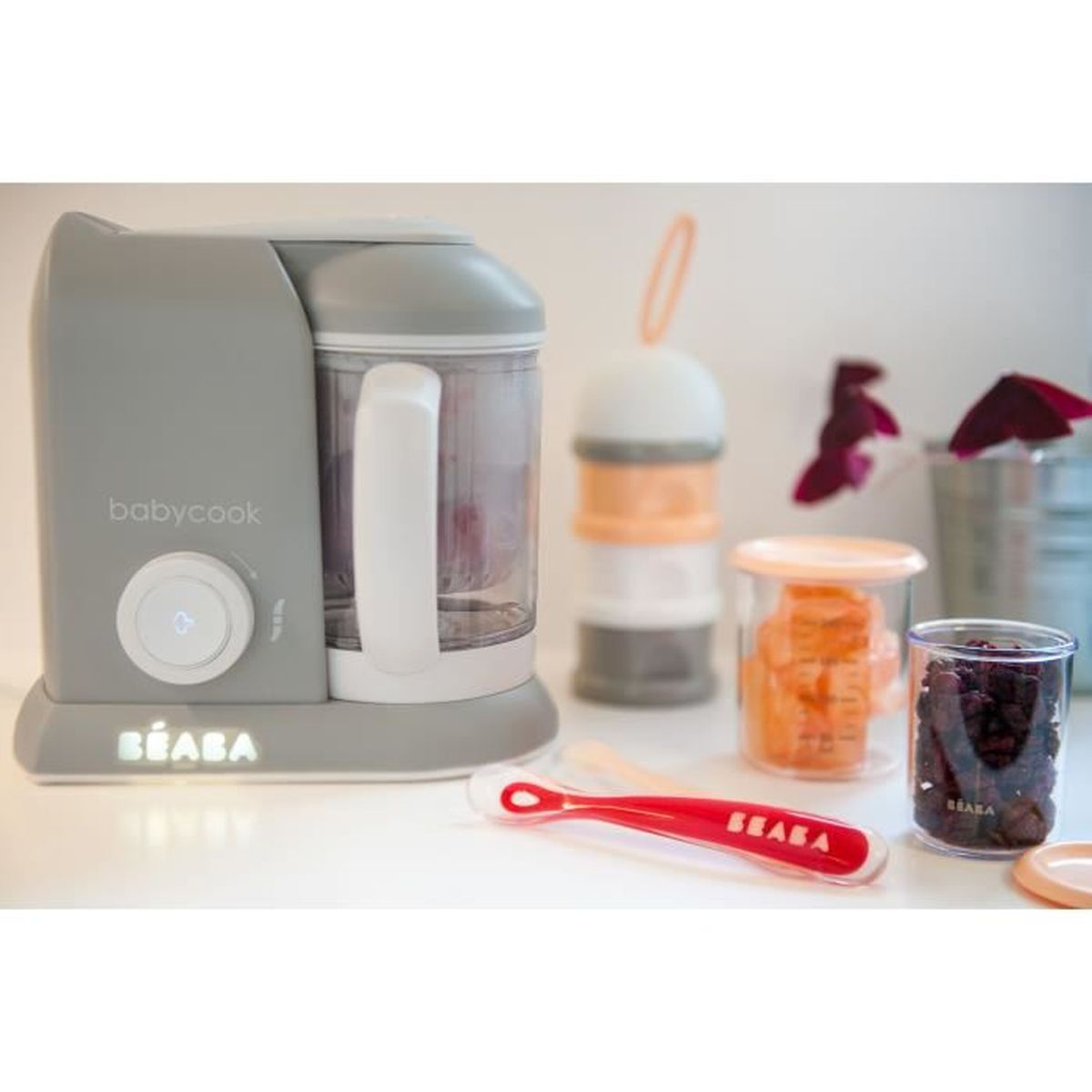 Ein grauer Babycook-Mixer mit Zubehör wie Löffeln und Behältern.