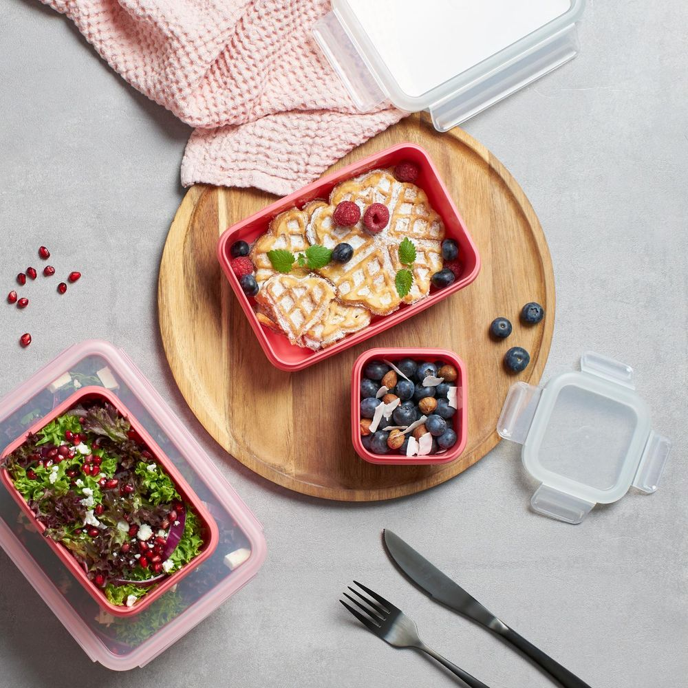 Herzwaffeln mit Beeren, Salat und Nüssen in Vorratsbehältern auf einem Holzteller.