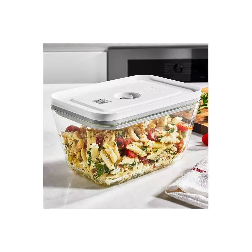 Un recipiente rectangular de vidrio lleno de ensalada de pasta, sobre una encimera.