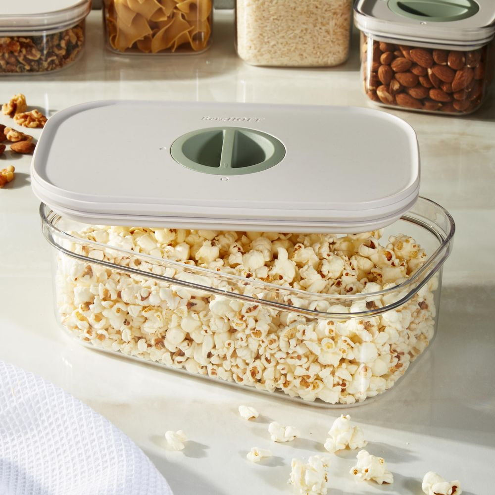 A clear container filled with popcorn, topped with a light gray lid.