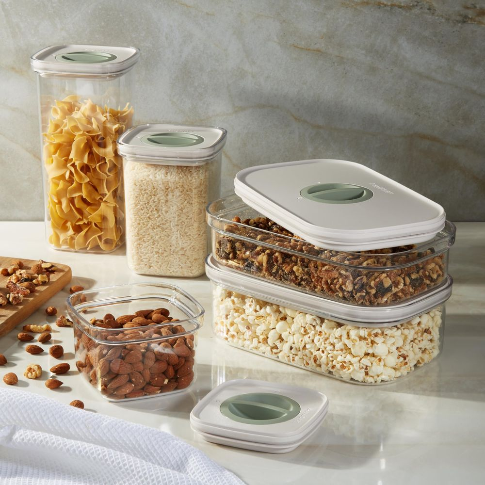 Clear food storage containers with various dry goods like pasta, rice, nuts, popcorn and almonds.