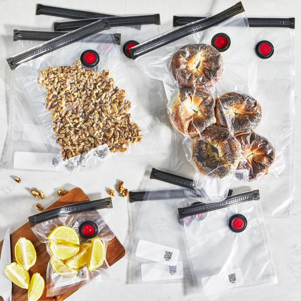 Nueces, bagels y rodajas de limón en bolsas selladas al vacío sobre mármol.