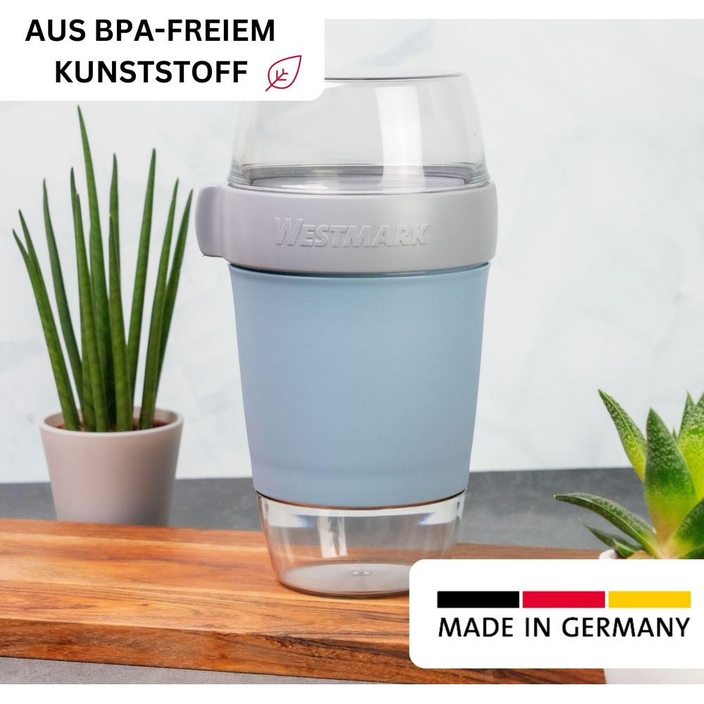 Ein blauer Westmark-Becher mit transparentem Deckel und Boden, auf einem Holzbrett.