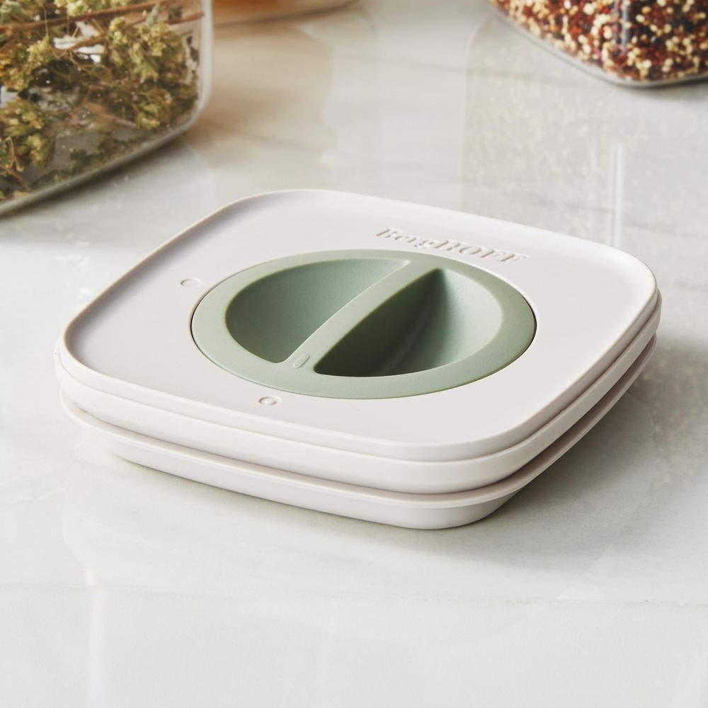 A white and green two-compartment container on a marble surface.