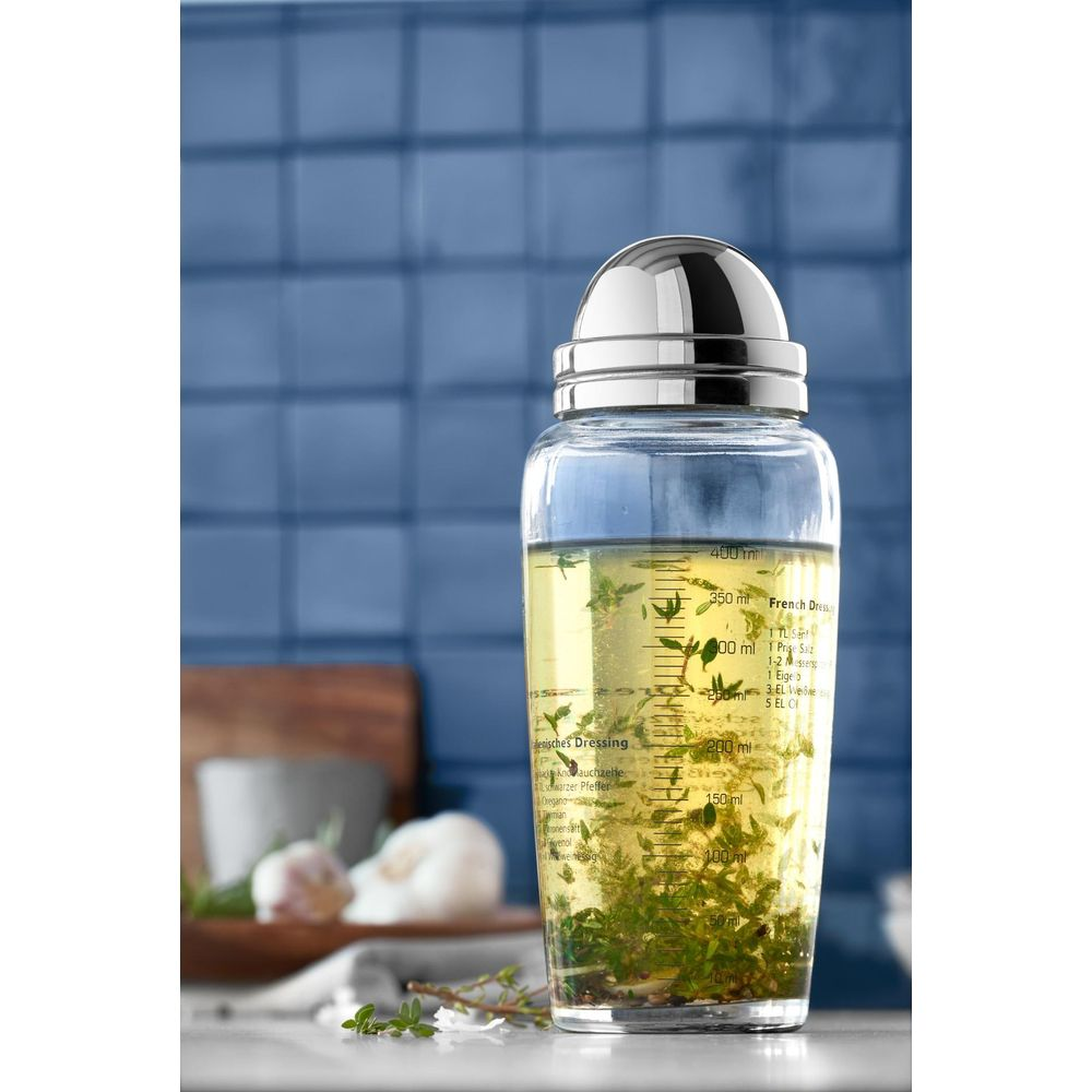 Ein Glasflaschen-Dressing-Shaker mit Kräutern und einer Skala.