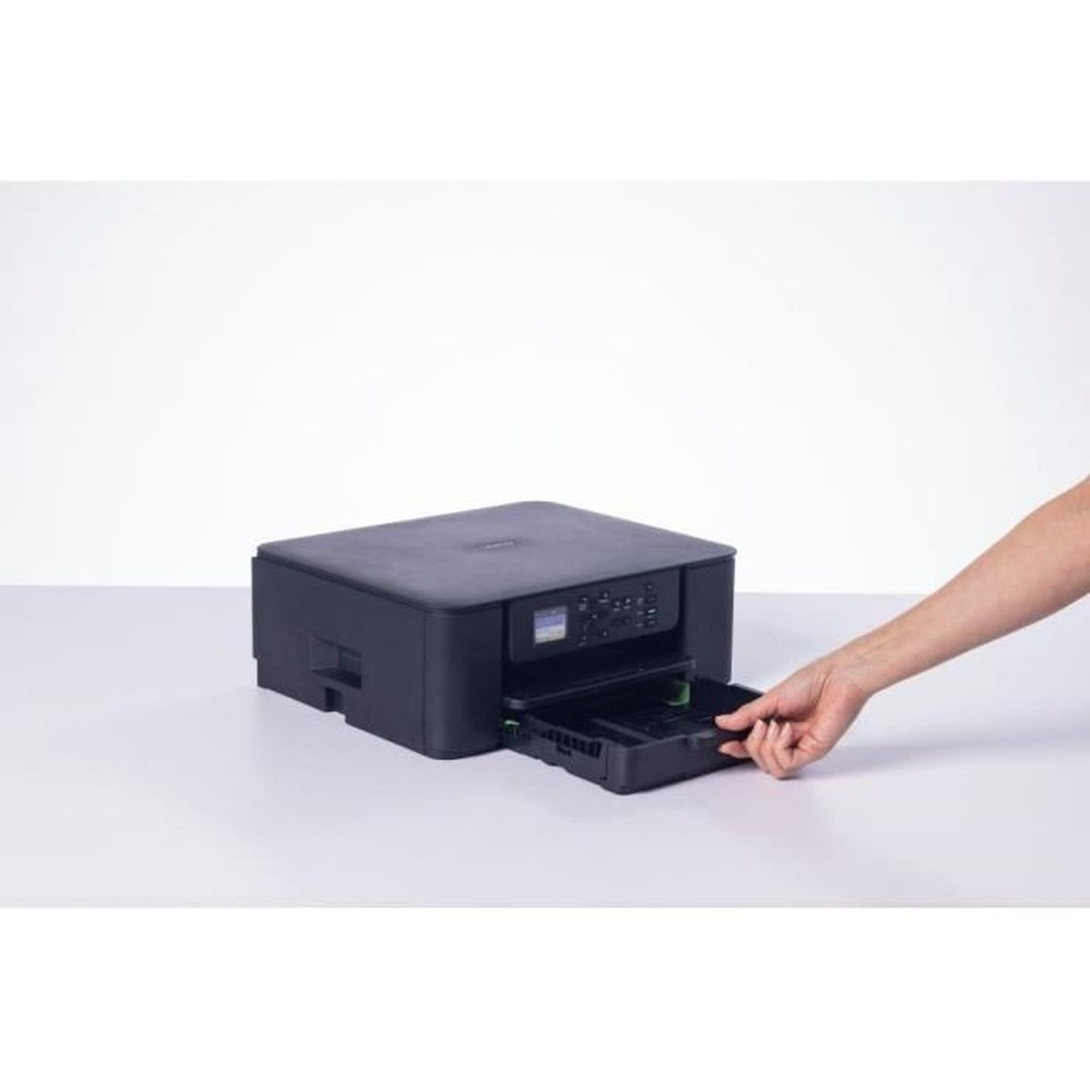 Ręka wyciąga szufladę z czarnej drukarki na białym stole.