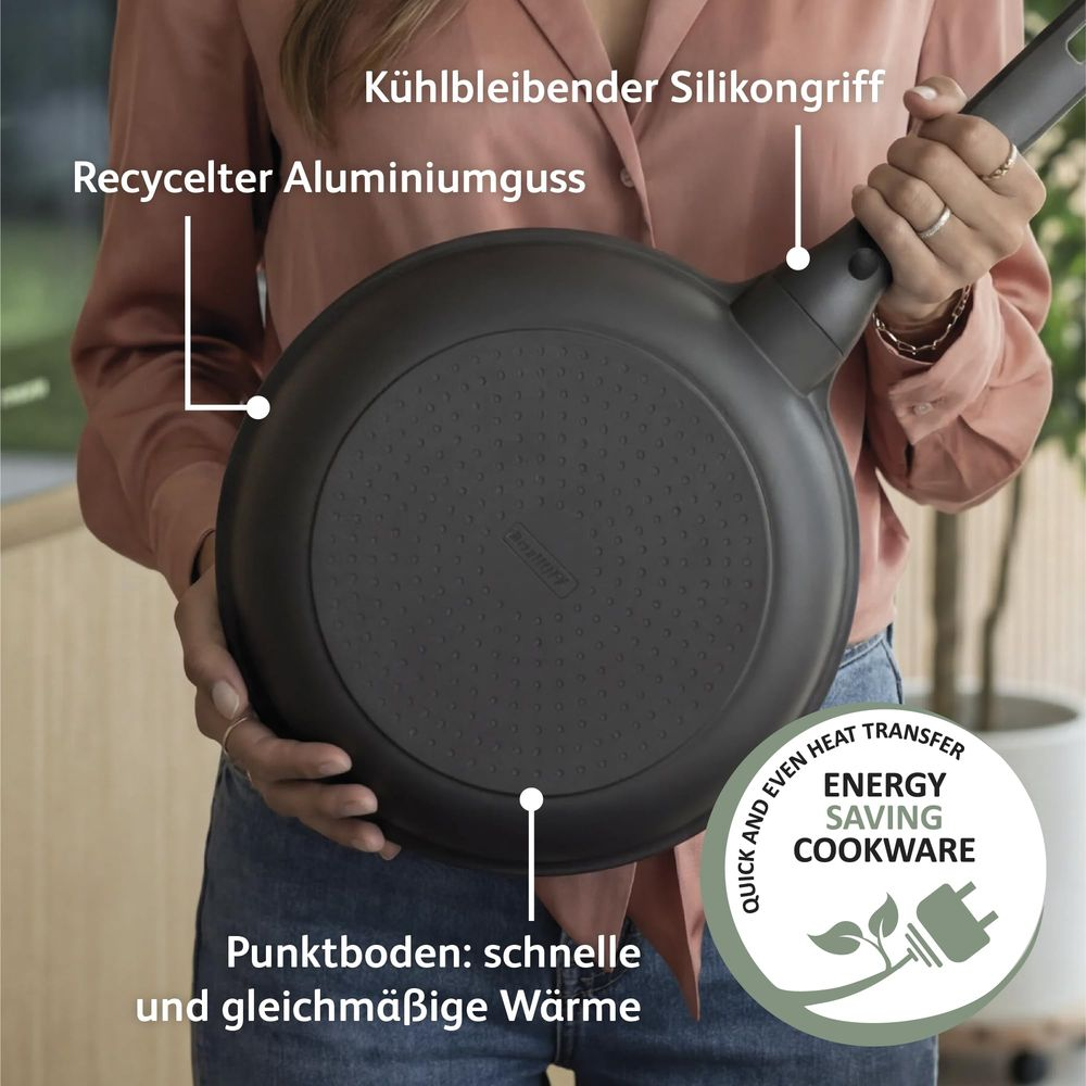 A person holds a black frying pan with a silicone handle, highlighting recycled aluminum.