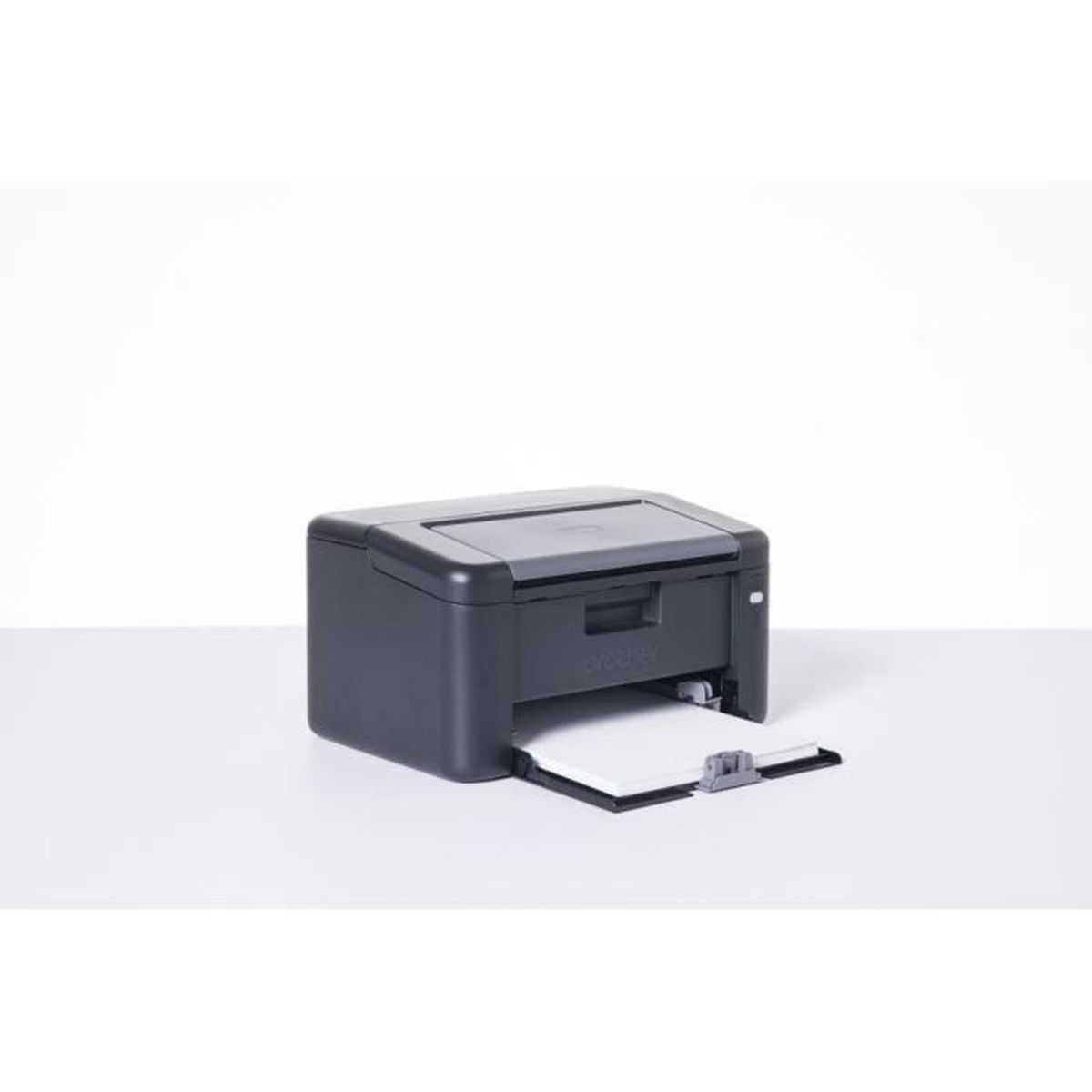 Czarna drukarka Brother z wysuniętą tacką na papier na białym stole.