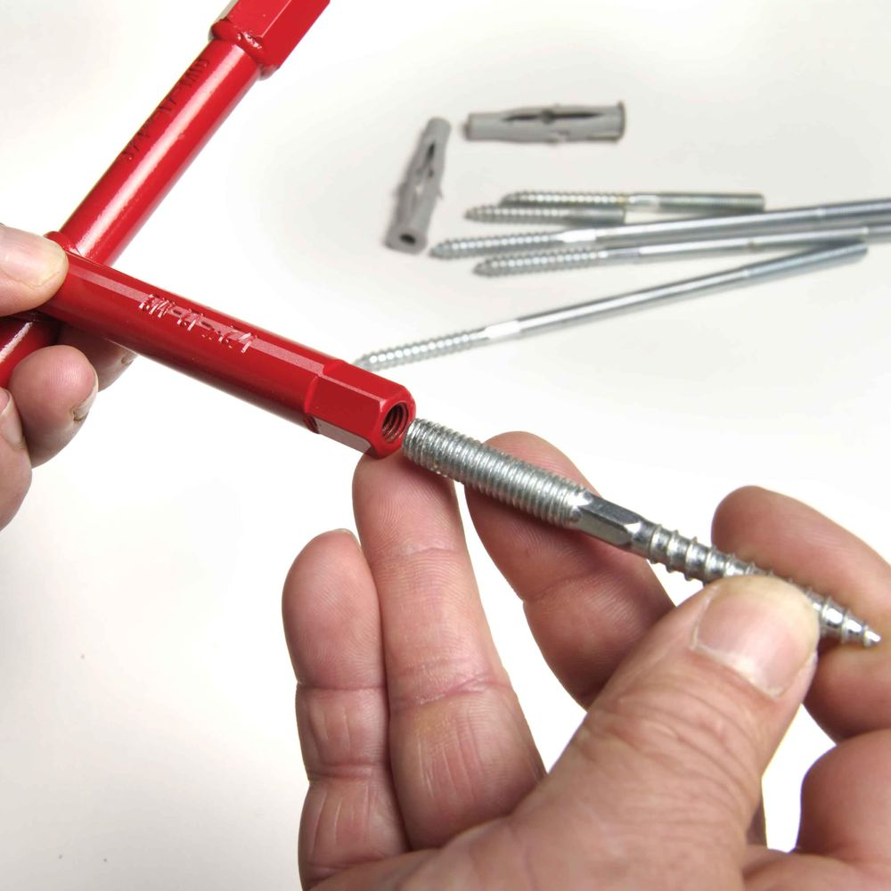 Roter Schraubenschlüssel verbindet sich mit Gewindestift. Dübel und Stifte im Hintergrund.