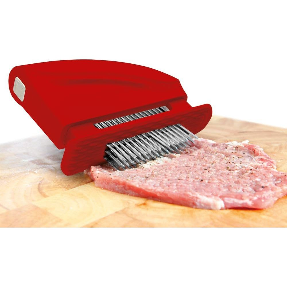 Roter Fleischklopfer mit Nadeln auf einem Stück Fleisch auf einem Holzbrett.