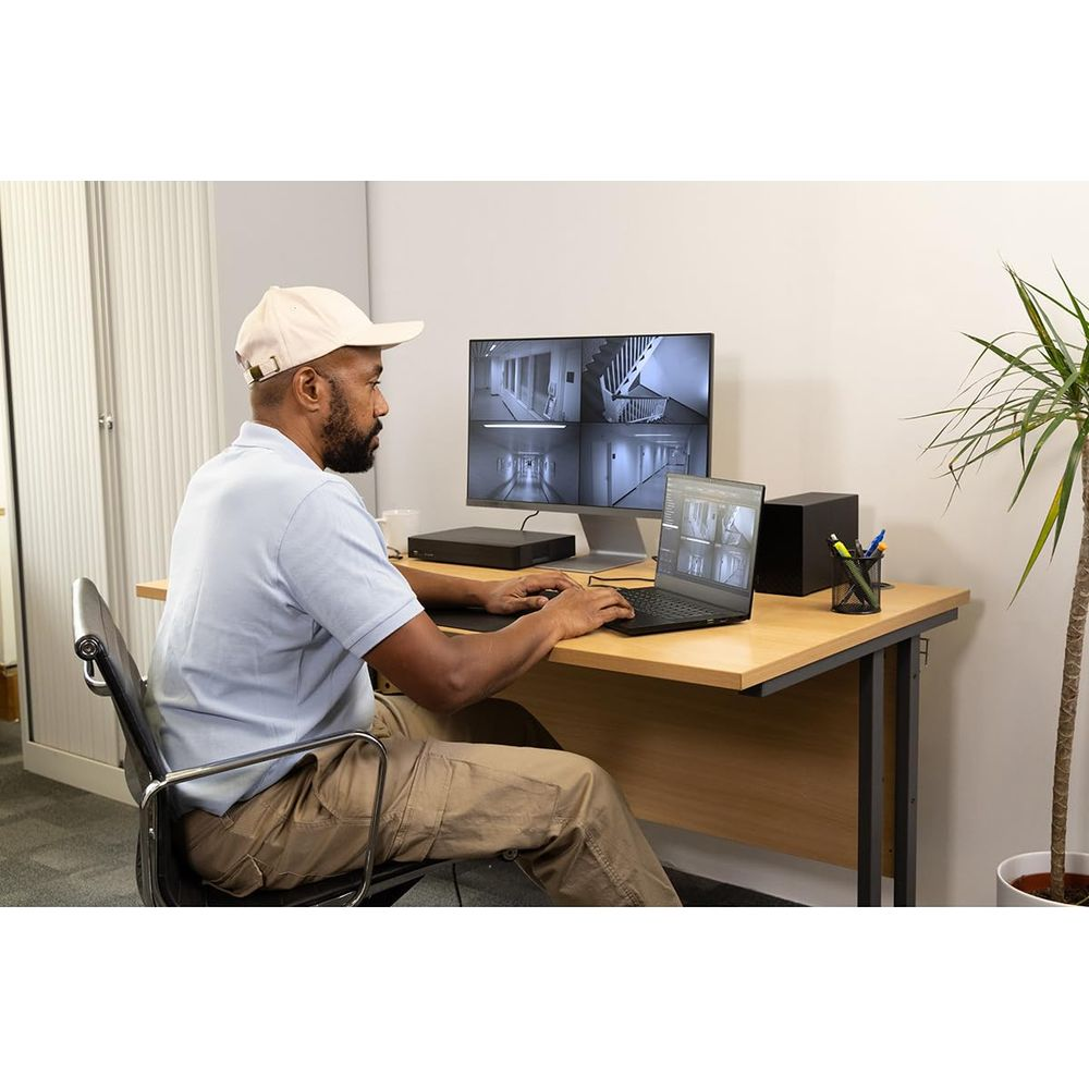 Mężczyzna siedzi przy biurku i patrzy na monitory z obrazem z monitoringu.