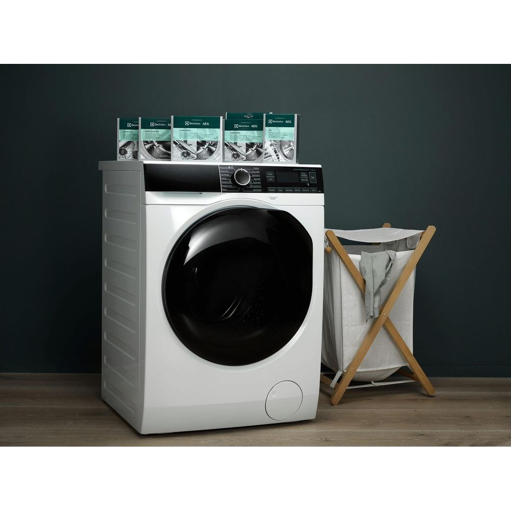 Une machine à laver blanche avec une porte noire à côté d'un panier à linge.