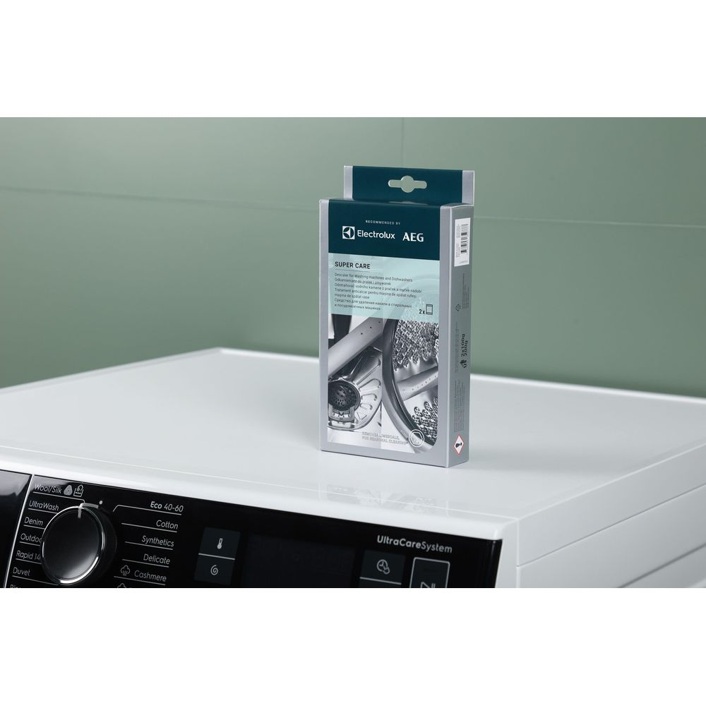 Boîte de détartrant pour lave-linge et lave-vaisselle sur un lave-linge blanc.