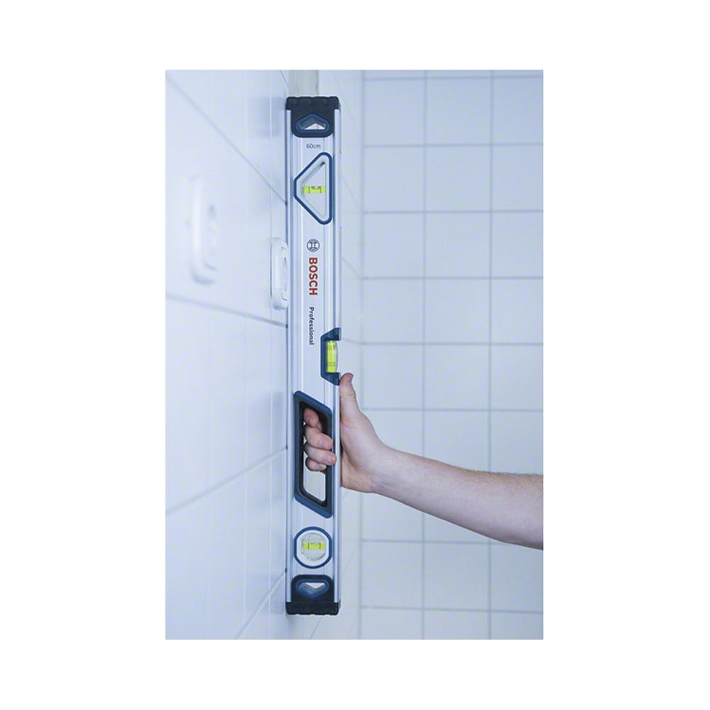 Dłoń trzyma poziomicę Bosch na ścianie z kafelkami.