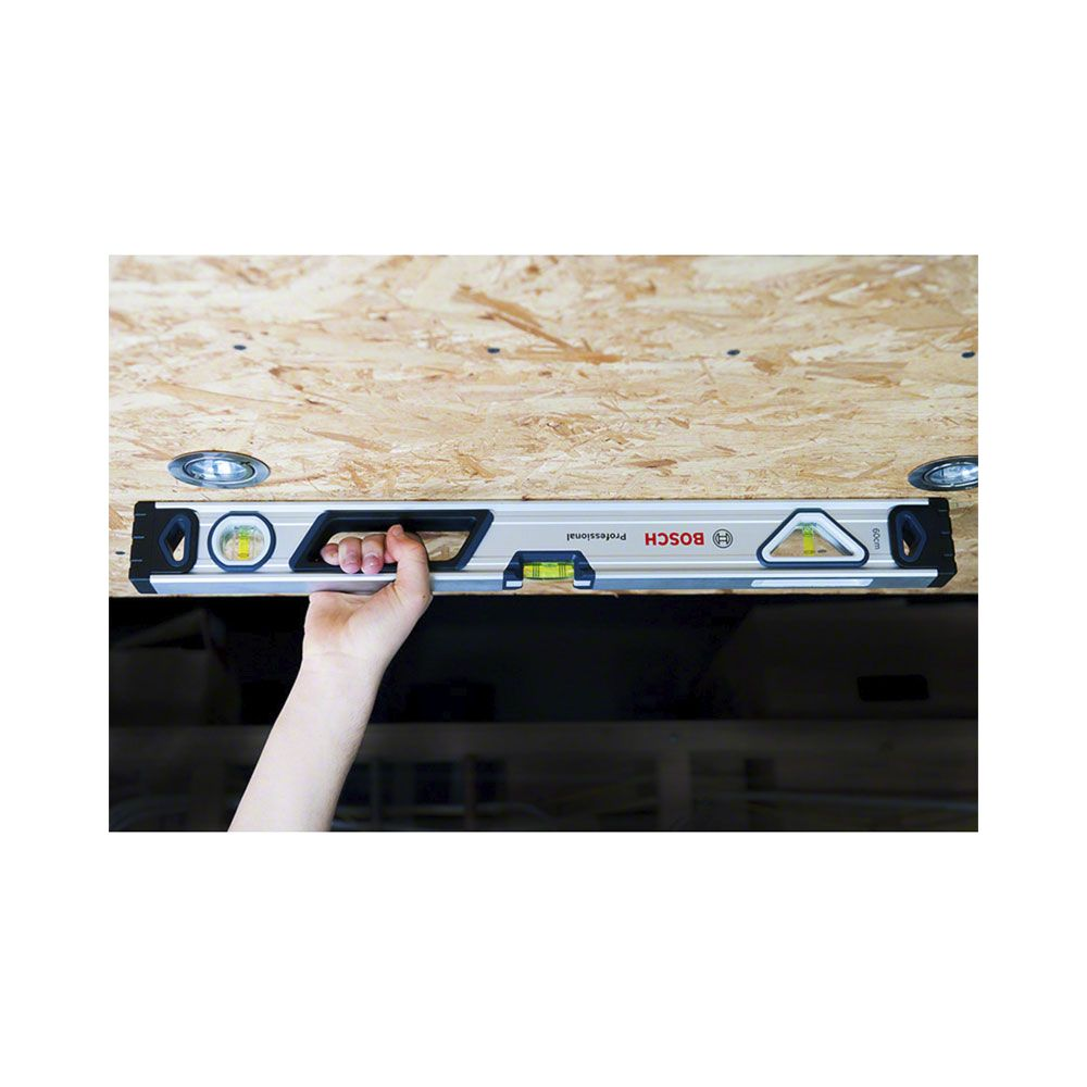 Ręka trzymająca poziomicę na drewnianym suficie z lampami.