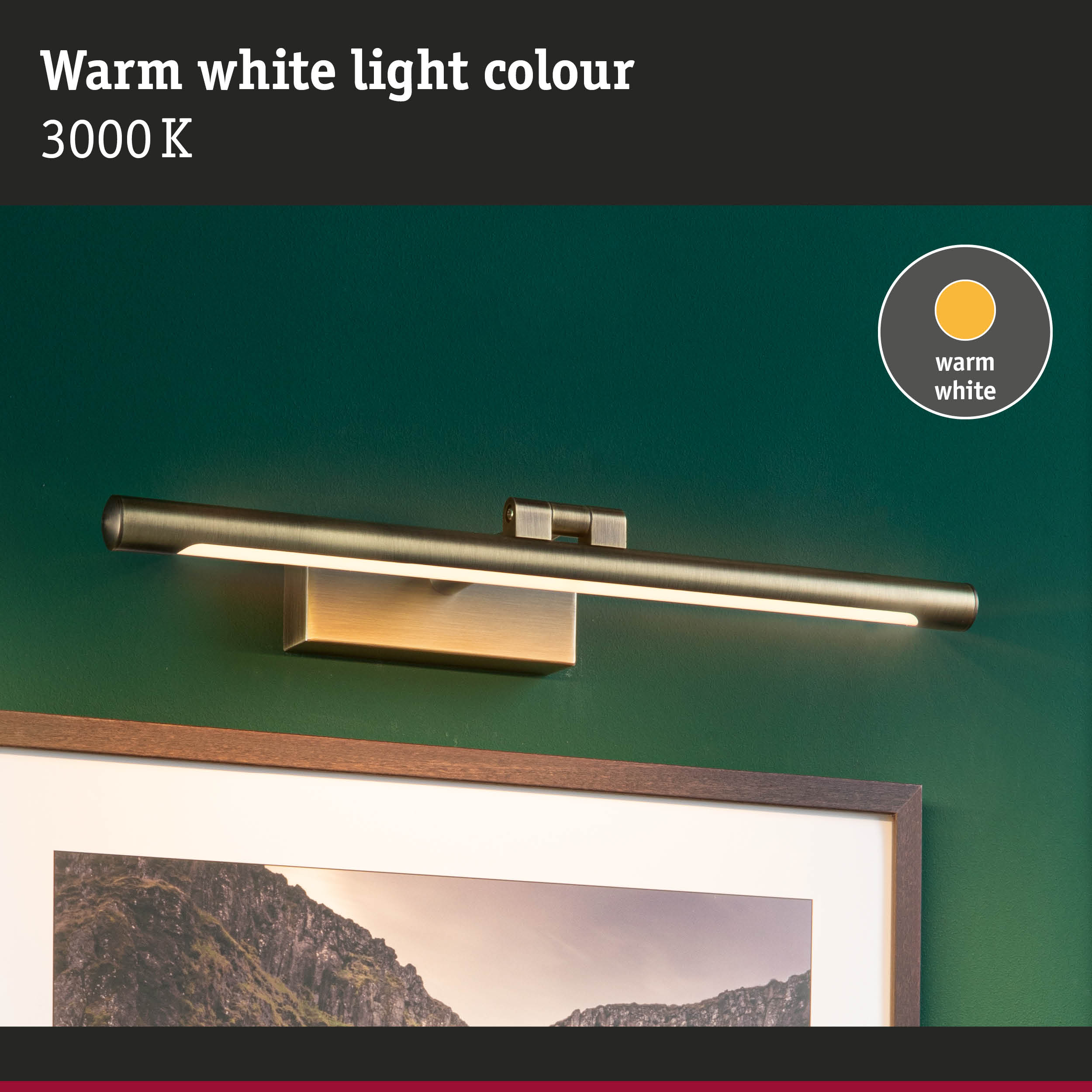 Nowoczesna mosiężna lampa ścienna nad oprawionym obrazem gór.