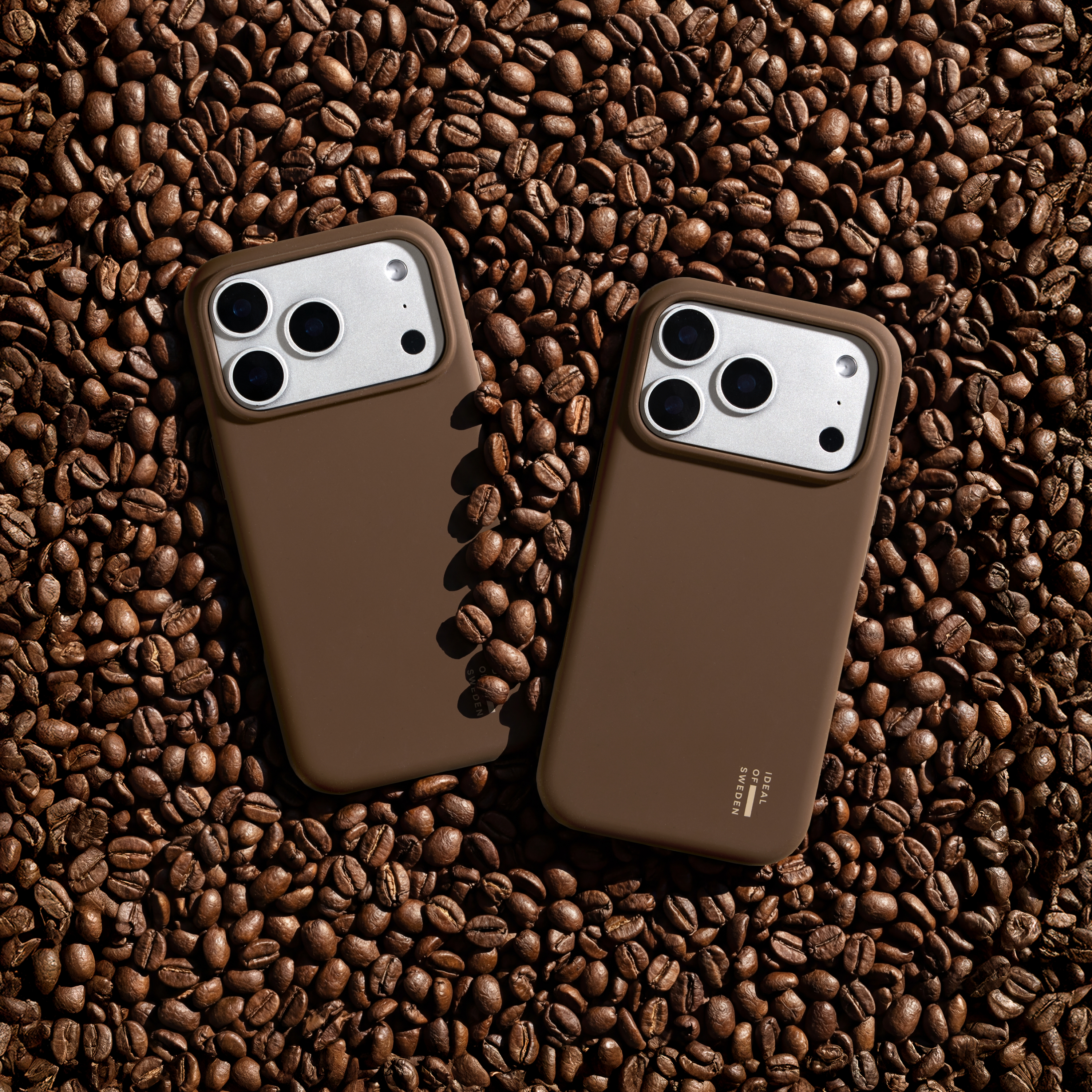 Zwei braune Handyhüllen liegen auf Kaffeebohnen.