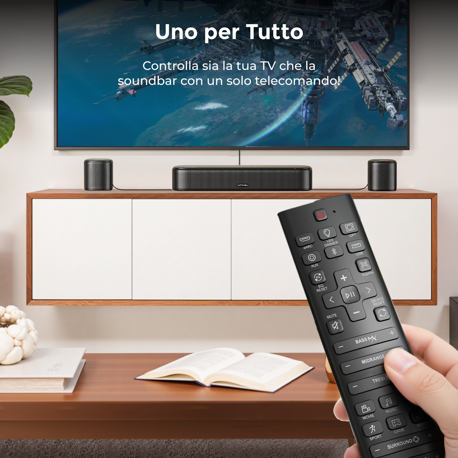 Una mano tiene un telecomando davanti a un TV, soundbar e due altoparlanti.